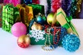 Beautiful Christmas decorations, toys, beads, balls in a box in foreground. Behind them there are gift bags and colorful tinsel.