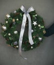 Christmas fir wreath in female hands on grey background Royalty Free Stock Photo