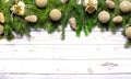 A beautiful Christmas garland made of fir trees with golden Christmas balls, hearts and cones on a light wooden background. Royalty Free Stock Photo