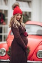 Beautiful Christmas pregnancy young woman in red hat posing outdoor at vintage car background Royalty Free Stock Photo