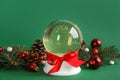 Beautiful Christmas snow globe and festive decor on green background Royalty Free Stock Photo