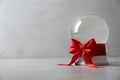 Beautiful Christmas snow globe with red bow on grey table Royalty Free Stock Photo