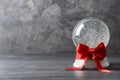 Beautiful Christmas snow globe with red bow on grey wooden table Royalty Free Stock Photo