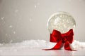 Beautiful Christmas snow globe with red bow on table against light background Royalty Free Stock Photo