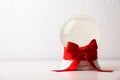 Beautiful Christmas snow globe with red bow on table against light background Royalty Free Stock Photo