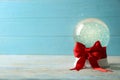 Beautiful Christmas snow globe with red bow on white wooden table against blue background Royalty Free Stock Photo