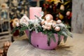 Beautiful Christmas table decorative composition with candle, toy deer, glass balls and fir tree in pink vase Royalty Free Stock Photo