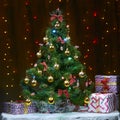 A beautiful Christmas tree and gifts against the background of red and yellow bulbs Royalty Free Stock Photo