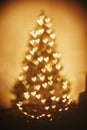 Beautiful christmas tree golden lights hearts in festive room. c Royalty Free Stock Photo