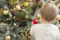 Beautiful Christmas tree with golden and red decoration. Image out of focus of a little girl from behind holding red ball Royalty Free Stock Photo