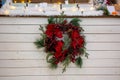 A beautiful Christmas wreath of coniferous fir branches, red berries and flowers in hoarfrost hanging on the background