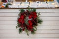 A beautiful Christmas wreath of coniferous fir branches, red berries and flowers in hoarfrost hanging on background of