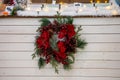 A beautiful Christmas wreath of coniferous fir branches, red berries and flowers in hoarfrost hanging on background of Royalty Free Stock Photo