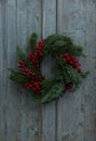Beautiful Christmas wreath with red berries hanging on wooden wall Royalty Free Stock Photo