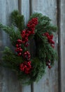 Beautiful Christmas wreath with red berries hanging on wooden wall Royalty Free Stock Photo