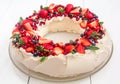 Beautiful Christmas wreath shaped Pavlova cake made of french meringue, whipped cream, decorated with fresh berries