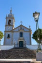Beautiful church with azulejo tiles on sunny day in Portugal. Catholic cathedral with bell, cross, clock and street lamp.