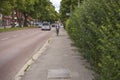 Beautiful city landscape view showing cyclist and cars on road on green trees background.