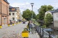 Beautiful city landscape view showing two cyclists and cars on road on side of river. Sweden.