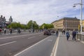 Beautiful cityscape view of downtown Stockholm on bright day. Pedestrians, bicycles and cars passing bridge. Sweden, Europe.