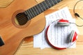 Beautiful classical guitar, headphones and music sheets on wooden background Royalty Free Stock Photo