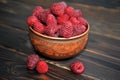 A beautiful clay pot with raspberries on a wooden table. raspberries in a plate.