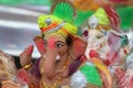 A Beautiful clay statue/Idol of an Indian god Lord Ganesha decorated with colorful drapery and Marigold garland