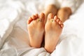 Baby& x27;s feet on a white bed with small daisies between the toes