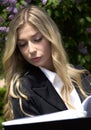 Beautiful clever woman hiding herself behind a book while sitting on the bench outdoor, close up portrait. lifestyle Royalty Free Stock Photo