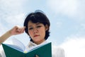 Asia woman holding and reading book on sky background. Royalty Free Stock Photo