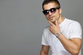 Beautiful close-up of a guy in a white cotton t-shirt and sunglasses on a gray background. Wrist watch isolated Royalty Free Stock Photo