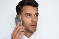 Beautiful close-up portrait of young man using mobile phone on gray background. Businessman speaking on his smart phone. Royalty Free Stock Photo