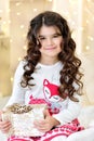 Beautiful close up portraite of curly girl with gold Christmas garlands magic lights and tree decorations gift box