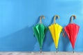 Beautiful closed colorful umbrellas near blue wall