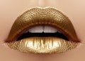 Beautiful closeup with female plump lips with gold color makeup. Fashion celebrate make-up, glitter cosmetic