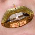 Beautiful closeup with female plump lips with gold color makeup. Glitter cosmetic. Golden ring with brilliant in mouth Royalty Free Stock Photo