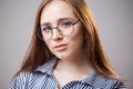 Beautiful closeup portrait of a young student girl wearing glasses on a gray background. Attractive redhead woman with natural Royalty Free Stock Photo