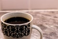 Beautiful closeup shot of a white cup with black patters filled with coffee