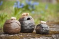 Beautiful closeup of unique handmade three pots on green moss in summer with blue flowers in background Royalty Free Stock Photo