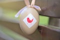 Closeup view of light beige plastic decorative Easter egg tied with ribbon on dark brown bench at university campus Royalty Free Stock Photo