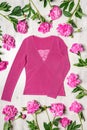 Beautiful clothing blouse in pink colors with fresh peonies flowers on light wooden background. Spring fashionable outfit, casual Royalty Free Stock Photo