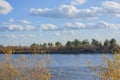 Beautiful clouds in the blue sky. Autumn landscape on a bright sunny day. Yellow and green trees on the bank of the blue river