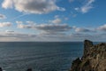 A tranquil scene of white clouds in a blue sky against the rugged coastline of Cornwall Royalty Free Stock Photo