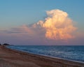 Beautiful cloudy landscape over the beach and the sea at sunset. A huge multicolored cloud in the shape of a tunnel at sunset. An