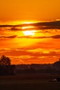 Beautiful cloudy red sunset with gigantic sun over big fields and trees seen by 600mm lens Royalty Free Stock Photo