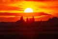 Beautiful cloudy red sunset with gigantic sun over big fields and trees seen by 600mm lens Royalty Free Stock Photo