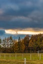 Beautiful cloudy sunset over big farm with fences and concrete poles at big green field at afternoon Royalty Free Stock Photo