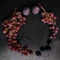 Beautiful clusters of black grapes and purple figs on a black table with drops, splashes of water, close-up, vitamins concept,