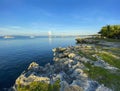 Beautiful coast with a rocky cliff, green grass and palm trees. Boats, yachts and ships in the sea against the blue sky