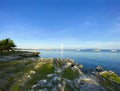 Beautiful coast with a rocky cliff, green grass and palm trees. Sunny summer weather. Boats, yachts and ships in the sea